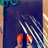 Feet on black yoga mat with sun streaks falling on mat.